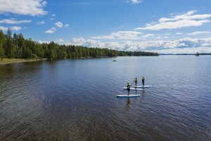 Sup-lautailijoita kesäisessä järvimaisemassa.