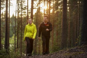 Pariskunta kävevee metsässä ilta-auringossa.