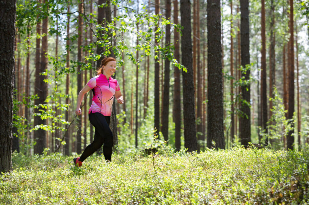 Nainen juoksee metsässä.